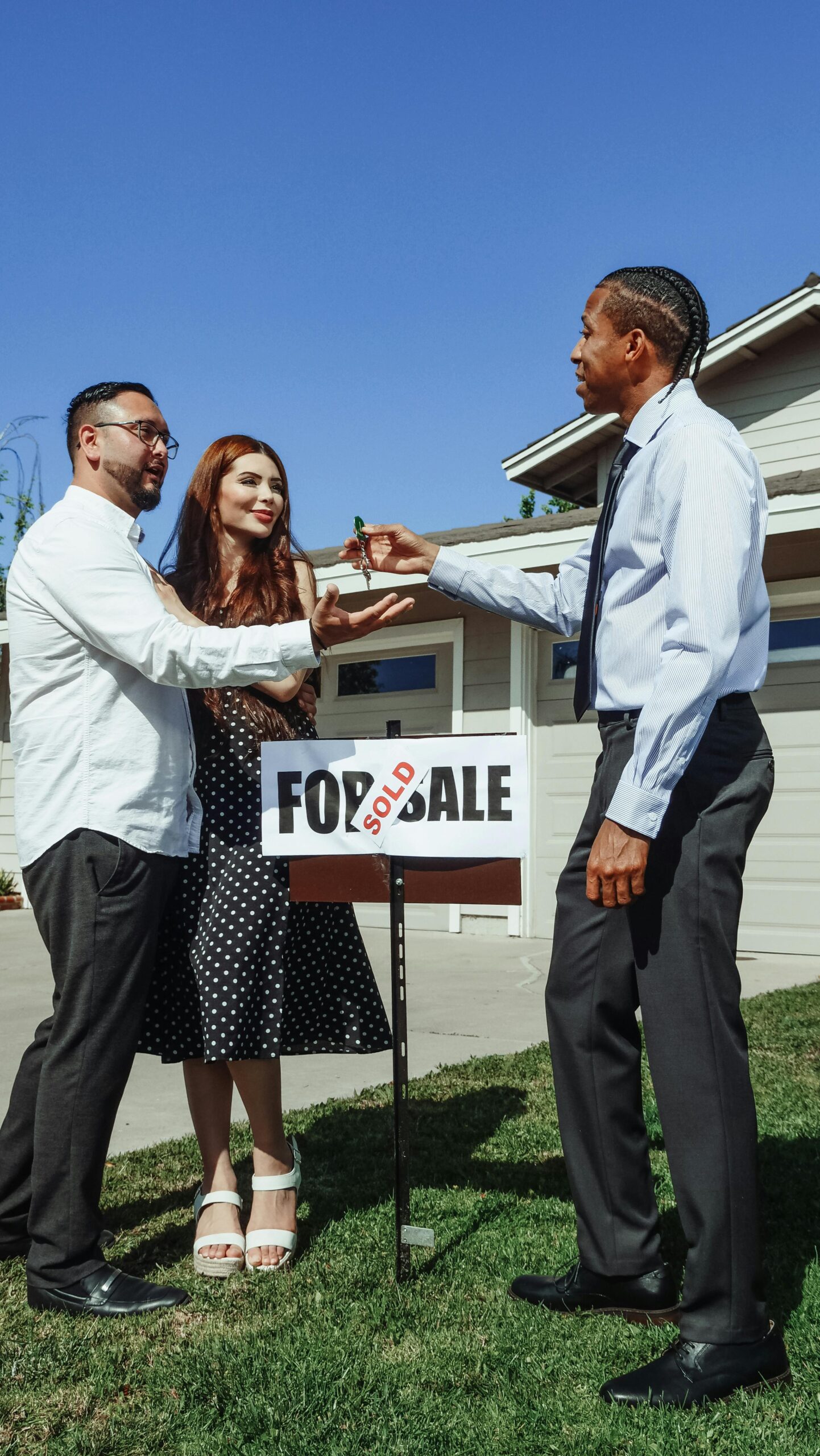 Couple receiving keys from realtor in front of newly sold house. Perfect real estate imagery.