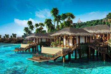 Scenic view of tropical overwater villas surrounded by clear blue water and palm trees in Vietnam.
